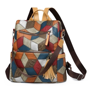 Detailed close-up of geometric color-block backpack with leather textures and fringe charm
