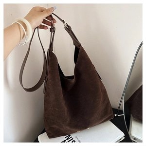 Detail view of dark brown suede tote bag with adjustable leather strap and metal buckle