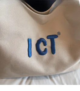 Detailed close-up of beige canvas tote bag featuring high-quality blue 3D logo embroidery