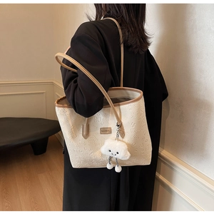 Dettaglio della borsa tote color crema con texture goffrate e spalline in pelle marrone