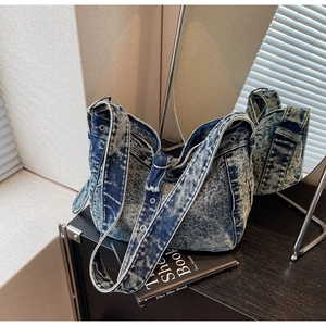 Detail of vintage washed denim hobo bag featuring wide strap and silver metal eyelets
