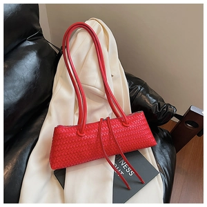 Detailed view of red woven leather baguette bag with dual handles on a stylish background