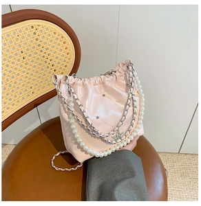 Détail d'un sac seau rose matelassé avec bandoulière perle et chaîne étoile sur chaise vintage