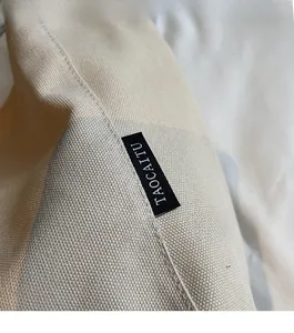 Detailed close-up of stitching and brand woven label on a beige canvas tote bag
