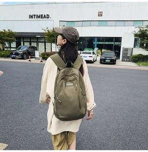 Street style view of military green canvas backpack showing large capacity and side pocket