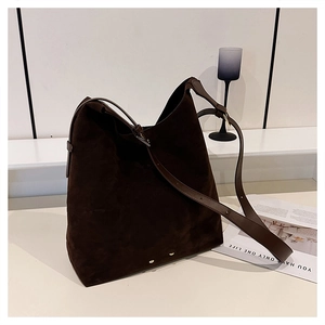 Close-up of vintage dark brown suede tote bag with adjustable strap and metal bottom studs