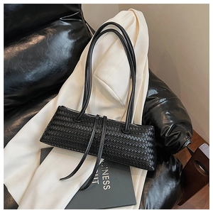 Detailed view of black woven faux leather texture and zipper on minimalist baguette bag
