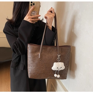 Dettaglio borsa shopper marrone con motivi cartoon goffrati e ciondolo a nuvola bianca