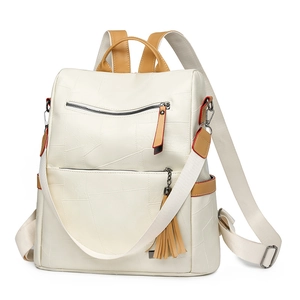 Detailed front view of beige travel backpack with brown trim and tassel accessory