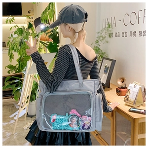 Detail of the large gray Ita bag featuring a transparent window and anime badges