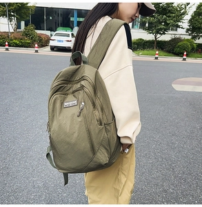 Outdoor shot of green nylon backpack with front zipper pockets and MACHUGE logo
