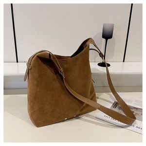 Close-up of brown suede bucket bag featuring adjustable straps and vintage metal rivets