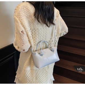 Light blue leather crossbody pillow bag with knot detail shown on a female model