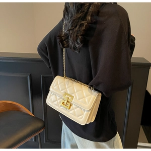 Sac à bandoulière matelassé crème avec chaîne dorée porté par le mannequin