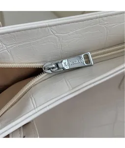 Nahaufnahme des silbernen Metallreißverschlusses mit Kalankol-Gravur auf weißem Shopper