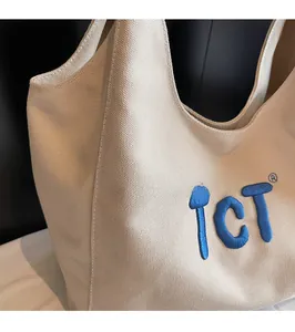 Close-up of cream canvas tote bag with 3D blue embroidered TCT logo and sturdy texture
