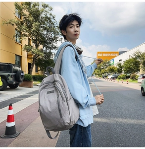 Outdoor shot showing a light grey large capacity nylon backpack for daily commuting