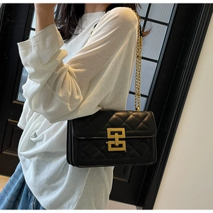 Détail d'un sac à bandoulière matelassé noir avec fermoir doré et bandoulière chaîne