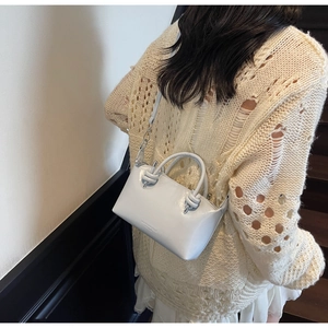 Light blue crossbody pillow bag with knot handles shown on a model in knitwear