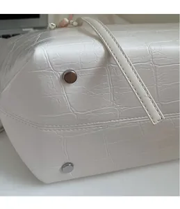Detailansicht der weißen Tasche mit Krokodilprägung und silbernen Metall-Schutznieten