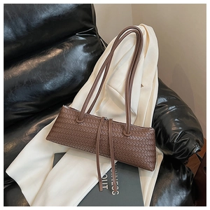 Macro detail of brown woven leather texture with tassels on a stylish shoulder bag