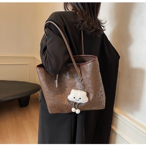 Dettaglio della borsa tote marrone scuro in ecopelle con goffratura cartoon e ciondolo
