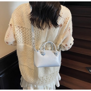 Close-up of a light blue crossbody bag with knot handle detail and silver metal hardware