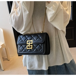 Détail du sac bandoulière en cuir noir matelassé avec chaîne dorée et boucle carrée