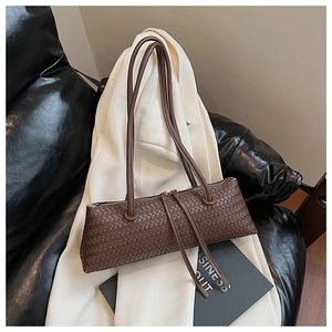 Detailed view of dark brown woven shoulder bag with double metal zippers on white blazer