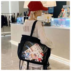 Detail of black ita-bag tote featuring a clear PVC window for doll and badge display