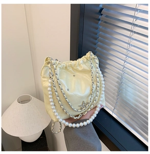 Détail du sac seau matelassé crème avec poignée en perles et breloque étoile en strass