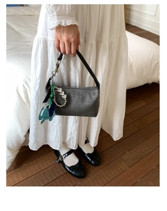 Detail of grey patterned canvas handbag with black leather strap and elephant charm