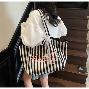 Détail du sac cabas rayé en toile avec motif Melody rose et nœud en dentelle