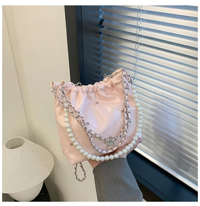 Détail du sac seau en cuir matelassé rose clair avec poignée perle et chaîne étoile