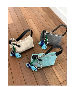 Three woven handheld pillow bags in cream, dark gray and light blue with elephant charms