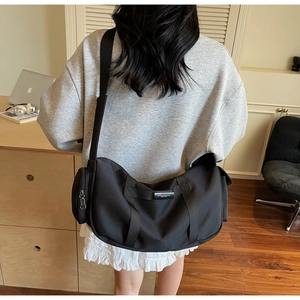 Dettaglio della borsa a tracolla in nylon nero con tracolla larga e tasche laterali zip