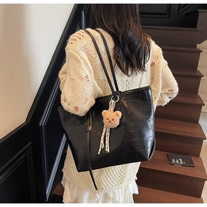 Detail of black stone-pattern tote bag featuring a cute bear plush keychain