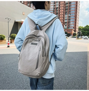 Detail of grey nylon backpack showing textured fabric, zippers, and brand label