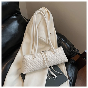 Detail of white woven leather underarm bag placed on a white blazer over a black chair