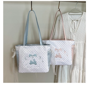 Close-up of lace ribbons and rabbit embroidery on polka dot canvas tote bags