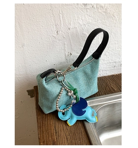 Close-up of woven light green texture with cute elephant leather charm and black strap