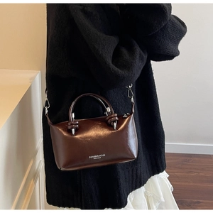 Detail of dark brown glossy pillow bag with silver hardware and knotted handle strap
