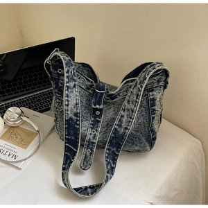Detail of vintage denim tote with snowflake wash, silver metal eyelets and wide shoulder strap