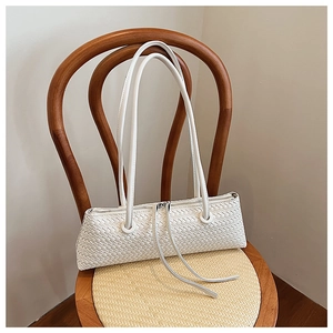 Detail of white woven leather underarm bag with long tassels on a vintage chair