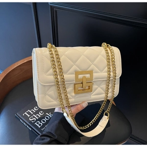 Détail du sac matelassé blanc cassé avec boucle dorée sur fond en cuir noir élégant