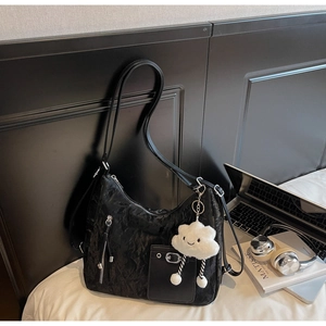 Detail of black pleated shoulder bag with silver zippers and a cute plush cloud charm