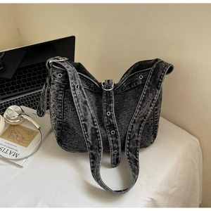 Detail view of denim tote bag featuring silver metal eyelets and a vintage punk style
