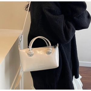 Detail view of beige glossy pillow bag with knotted handle and brand logo lettering