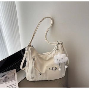 Detail of creamy white leather hobo bag with zip pocket and cute plush cloud charm