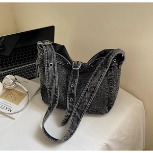Detail view of washed denim tote bag with metal eyelets on a styled desk setup